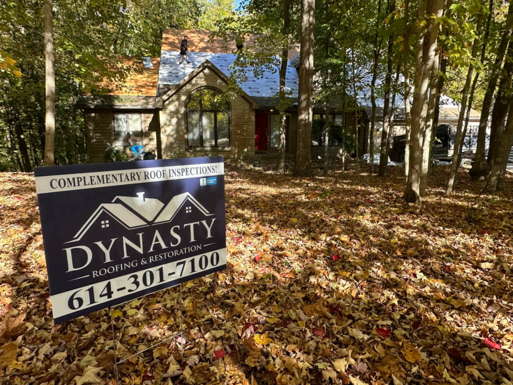 dynasty-roofing-yard-sign dynasty roofing yard sign in front of a home in the woods having its roof replaced